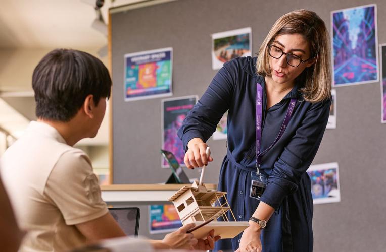 Teacher shows a small-scale architectural model of a building to student.